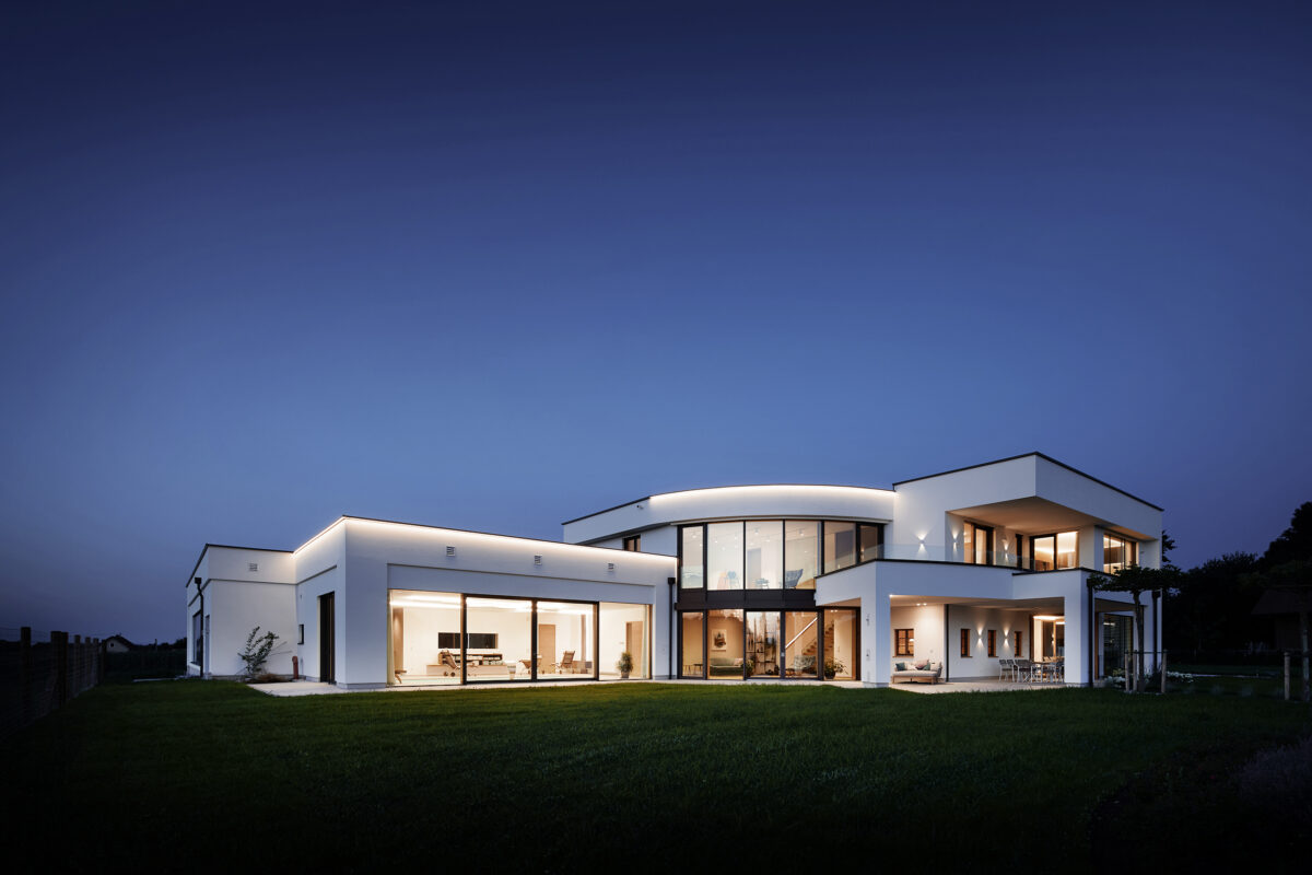 Exklusive Architekturfotografie bei Dämmerung: Große Glasfronten und Hebeschiebetüren von Palisa Bauelemente an einem modernen Wohnhaus mit Innenpool, fotografiert von Roland Wimmer.