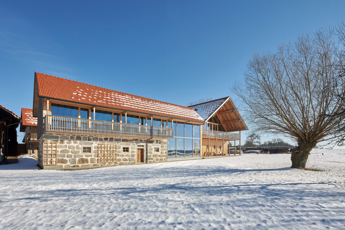 Moderne Sanierung eines traditionellen Hofes mit einer großflächigen Glasfassade und Fenstern von Böhler Fenster Vorarlberg in verschneiter Winterlandschaft, Architekturfotografie von Roland Wimmer.