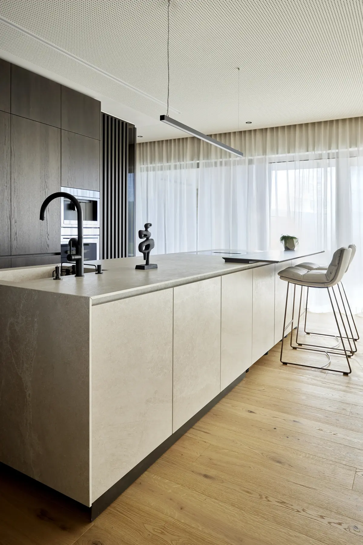 Moderne Kochinsel mit Naturstein-Arbeitsplatte und schwarzen Armaturen bei einem Wohnhaus in Steyr, gestaltet von Architekt Michael Obermair, professionelle Interieurfotografie von Roland Wimmer.