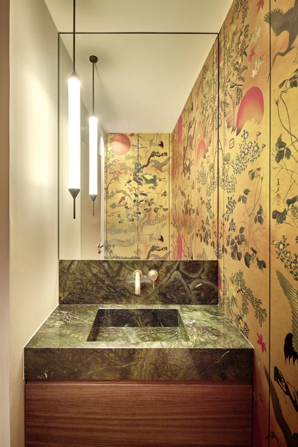 Gäste-WC mit Waschtisch aus grünem Marmor vor goldener Chinoiserie-Tapete mit Kranichmotiv, Wohnung in Bregenz von Gahleitner Architekten