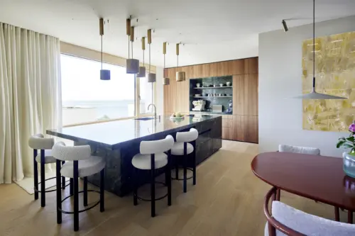 Offene Küche mit Marmorinsel und Barhockern vor bodentiefem Fenster mit Blick auf den Bodensee, Loft in Bregenz von Gahleitner Architekten