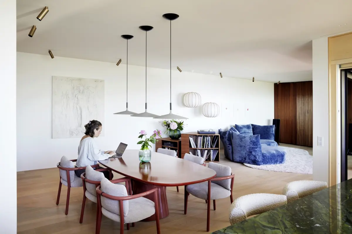 Offener Wohn- und Essbereich mit ovalem Esstisch, blauem Samtsofa und Nussbaum-Wandverkleidung, Loft in Bregenz von Gahleitner Architekten