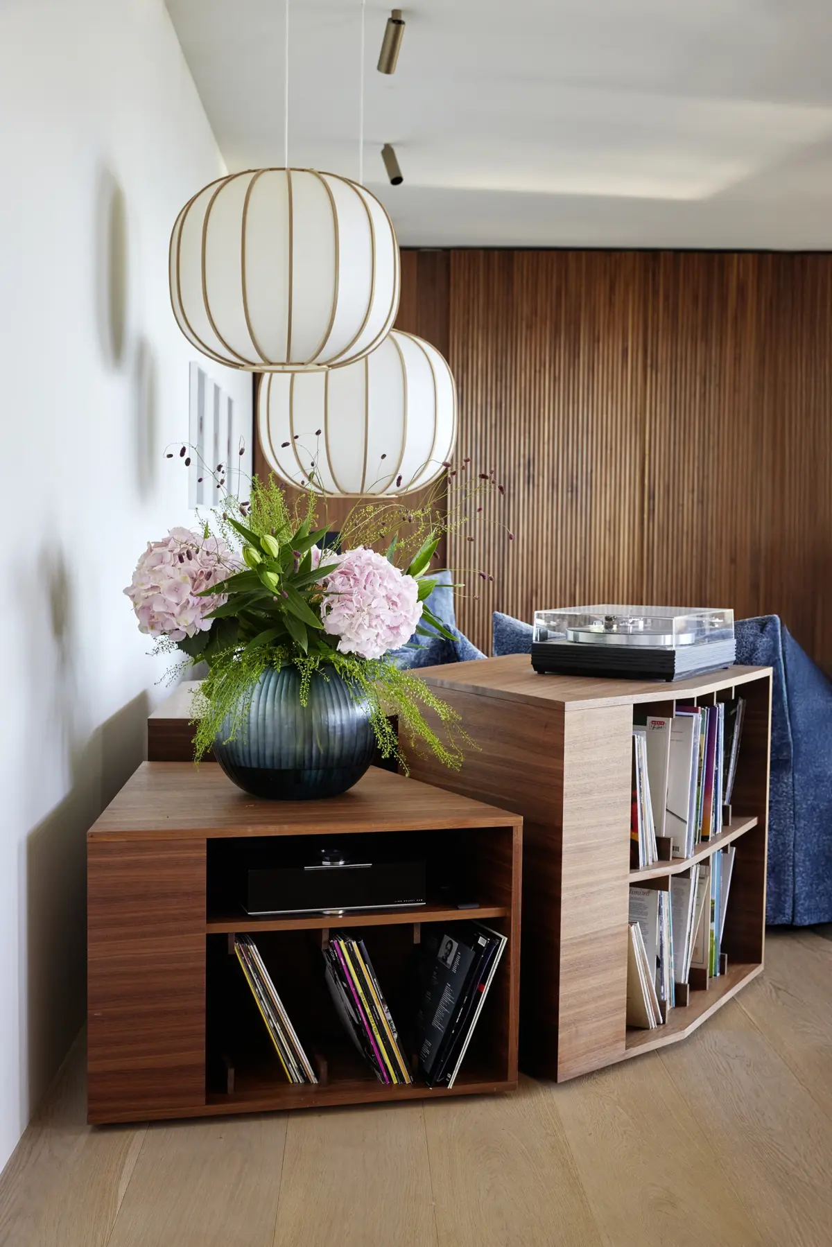 Maßgefertigtes Sideboard aus Nussbaum mit Plattenspieler und Schallplattenregal vor geriffelter Holzwand, Loft in Bregenz von Gahleitner Architekten