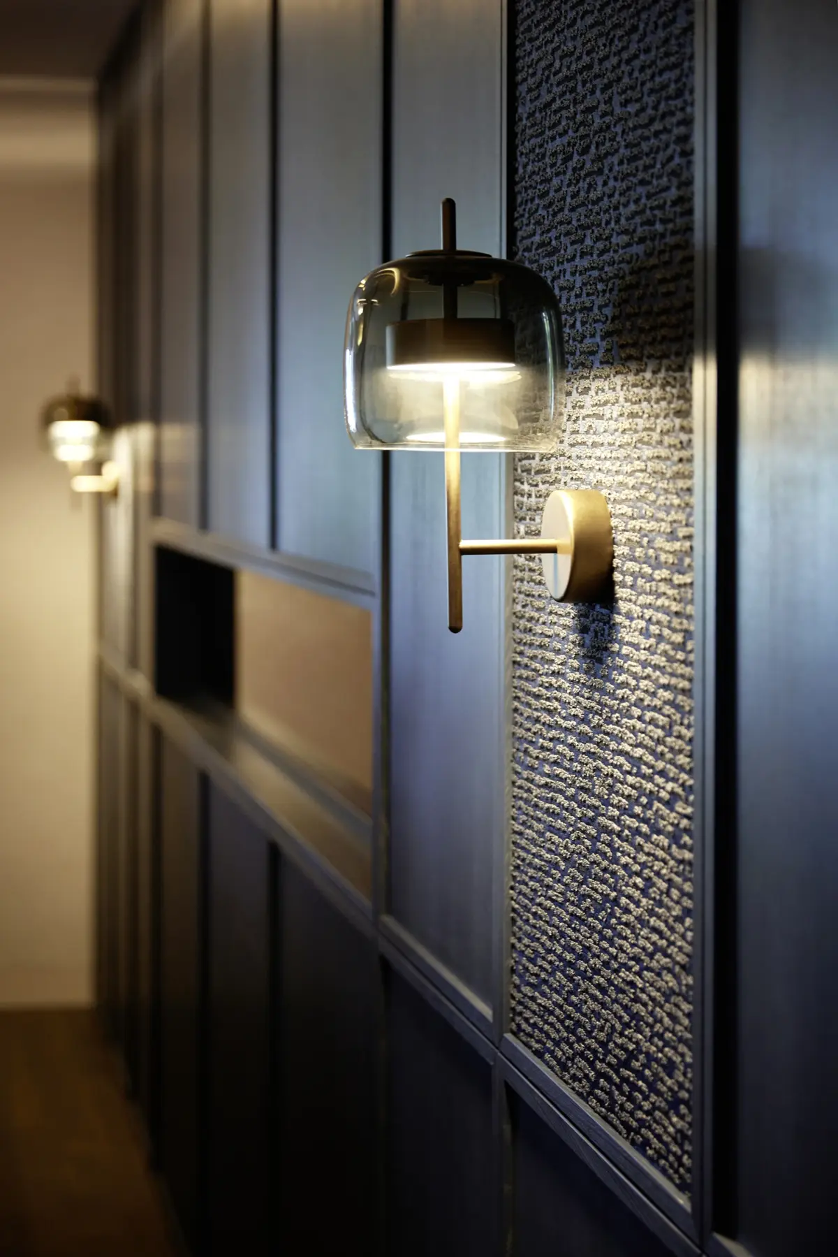 Wandleuchte aus Rauchglas und Messing vor strukturierter Wandverkleidung im Hotel Gierer, Wasserburg am Bodensee