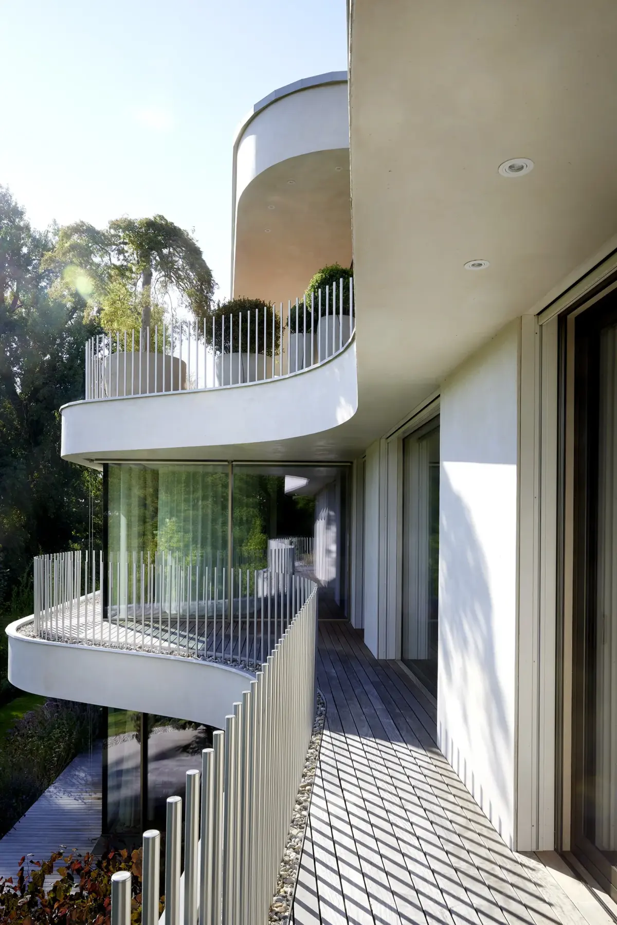 Geschwungener Balkon mit Holzdeck, Staketengeländer und Streiflicht einer Villa am Bodensee bei Bregenz, Gahleitner Architekten, Architekturfotograf Roland Wimmer