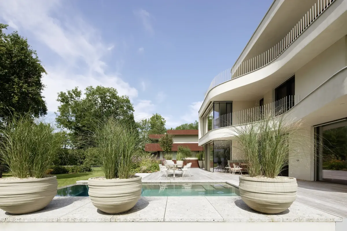 Pool mit großen Pflanzgefäßen und Holzterrasse vor der geschwungenen Fassade einer Villa am Bodensee bei Bregenz, Gahleitner Architekten, Architekturfotograf Roland Wimmer