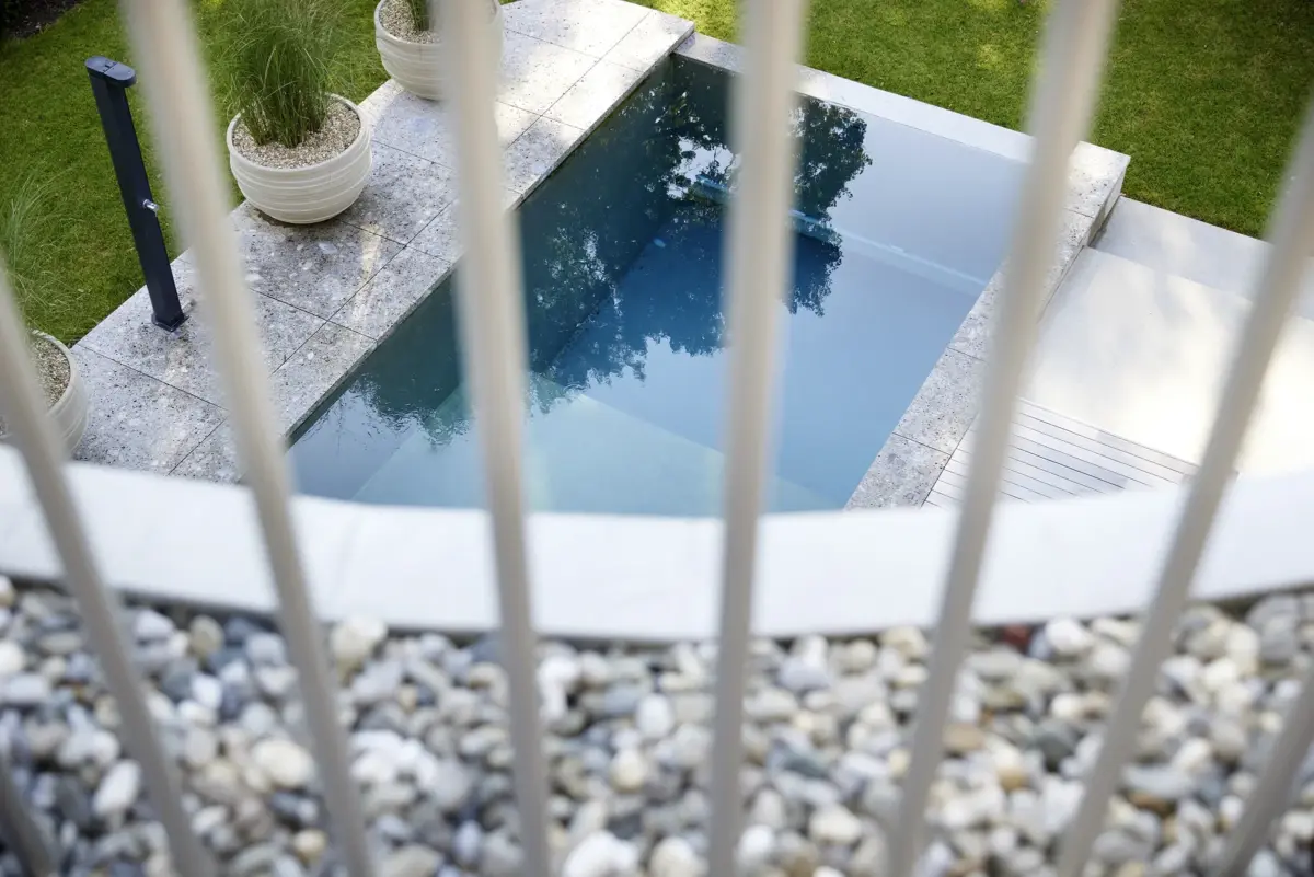 Blick durch das Geländer von oben auf den Pool mit Kiesstreifen einer Villa am Bodensee bei Bregenz, Gahleitner Architekten, Architekturfotograf Roland Wimmer