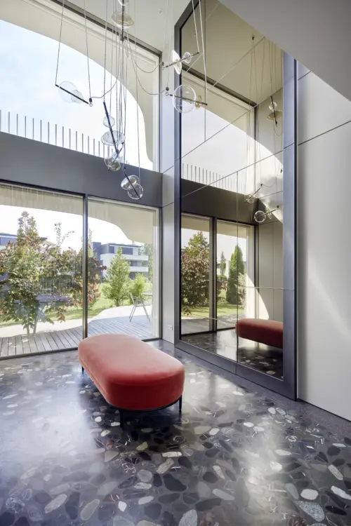 Doppelt hoher Eingang mit Terrazzoboden, roter Samtbank, Spiegelwand und Glasluster in einer Villa am Bodensee bei Bregenz, Gahleitner Architekten, Interieurfotografie Roland Wimmer