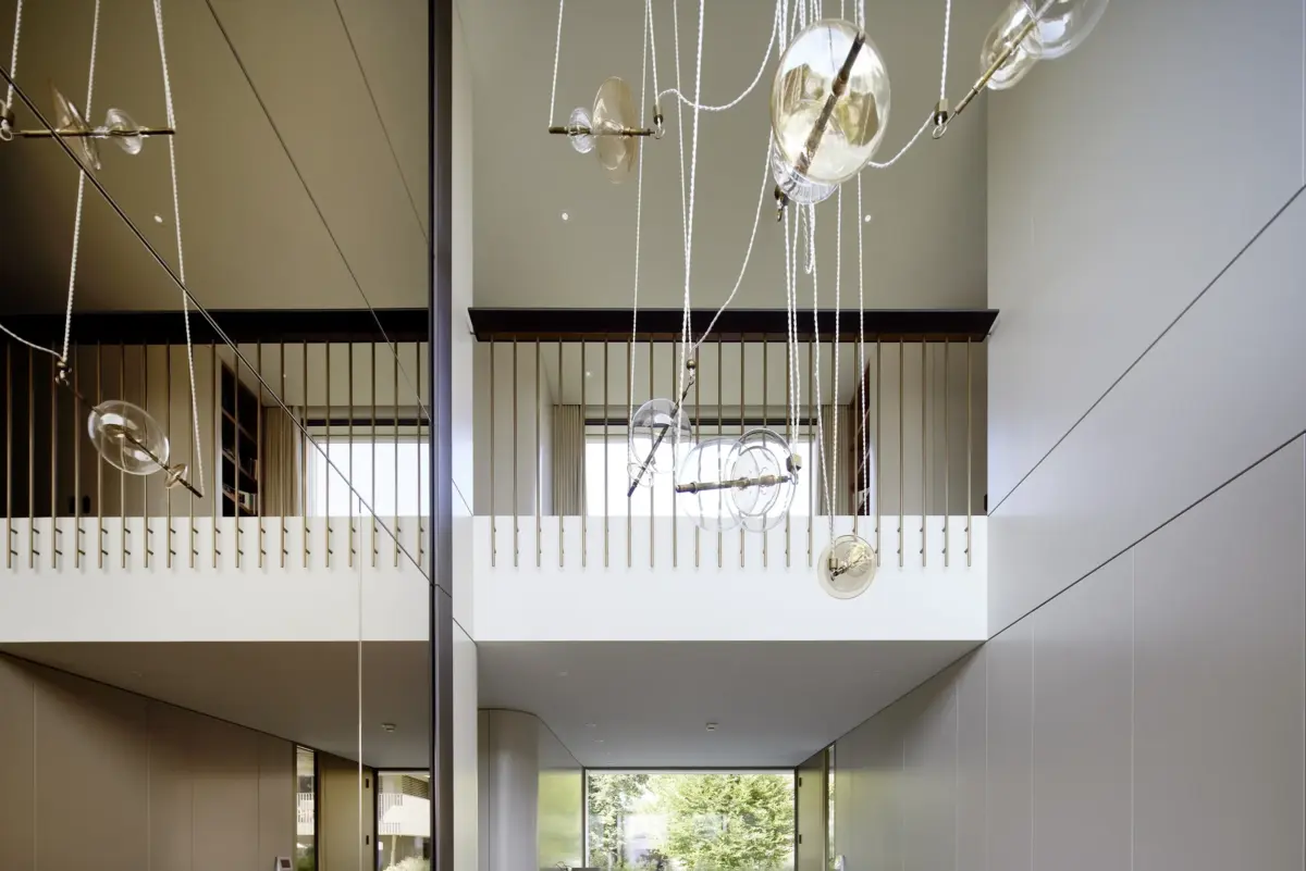 Luftraum mit Galerie, Messinggeländer und Glasluster aus mundgeblasenen Kugeln in einer Villa am Bodensee bei Bregenz, Gahleitner Architekten, Interieurfotografie Roland Wimmer