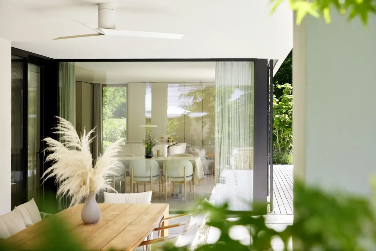 Blick von der überdachten Terrasse durch die raumhohe Glasfront in den Essbereich einer Villa in Bregenz, Gahleitner Architekten, Interieurfotografie Roland Wimmer