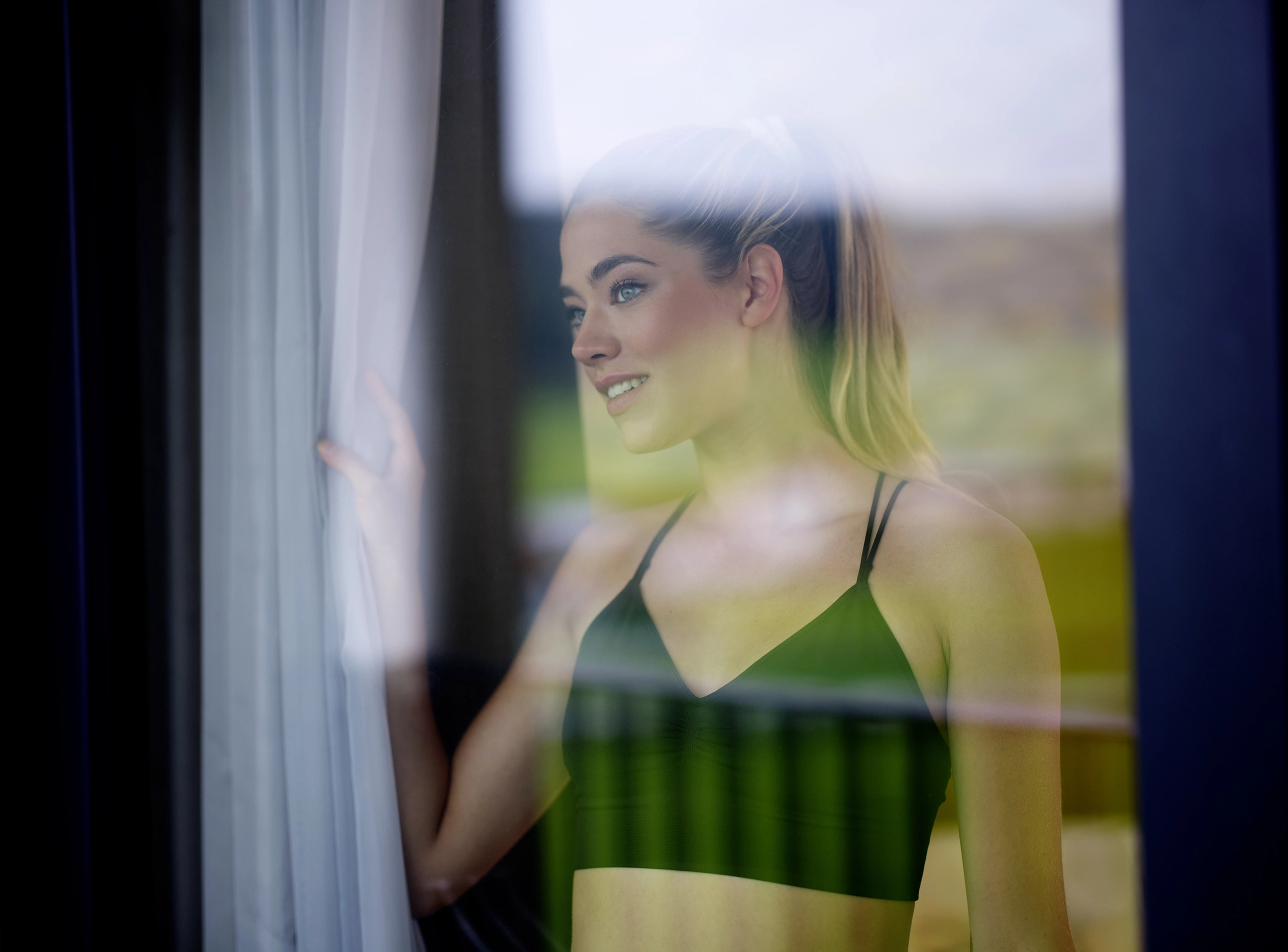 Frau blickt durch das Fenster aus dem Hotelzimmer